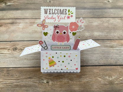 Decorative baby girl pop-up card with owl design on a wooden surface