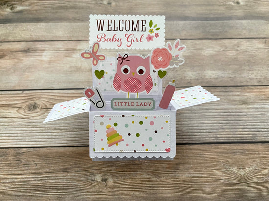 Decorative baby girl pop-up card with owl design on a wooden surface