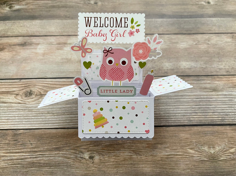 Decorative baby girl pop-up card with owl design on a wooden surface