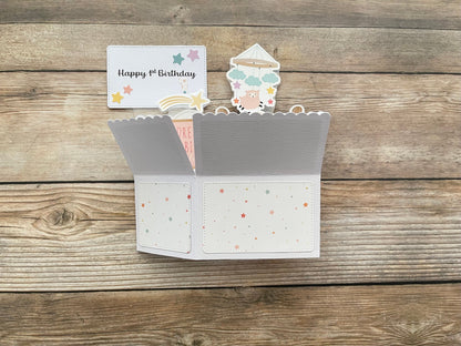 Folded pop-up card with decorative elements on a wooden surface
