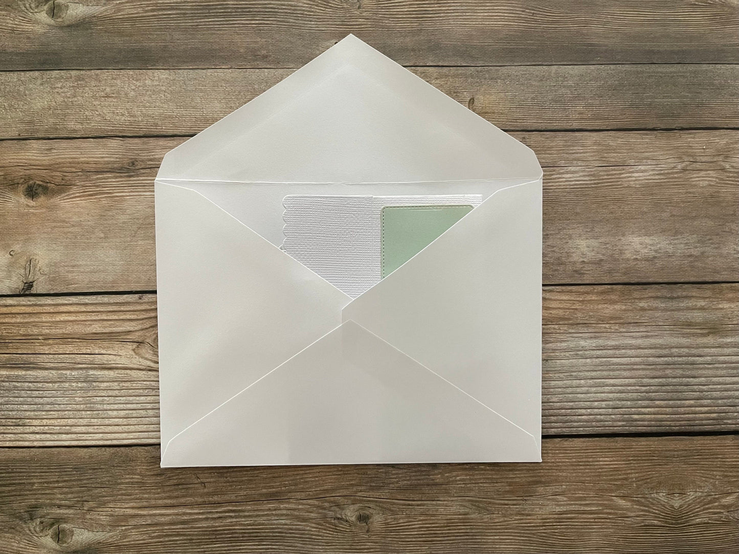 White envelope with a green card on a wooden surface