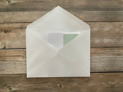White envelope with a green card on a wooden surface