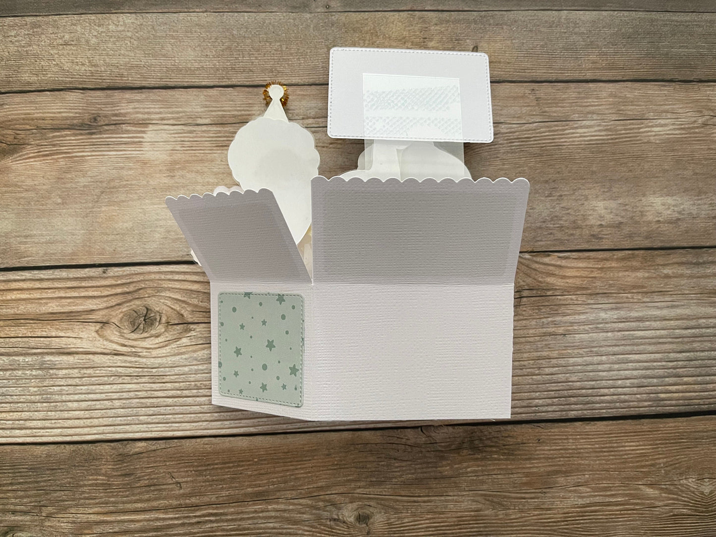 Back of a folded baby shower themed pop-up card on a wooden table.