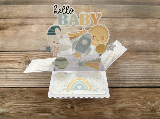 Pop-up baby card with space-themed design on a wooden surface