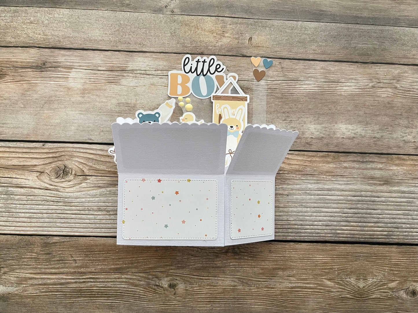 Open box style baby boy birthday pop-up card with decorative elements on a wooden surface