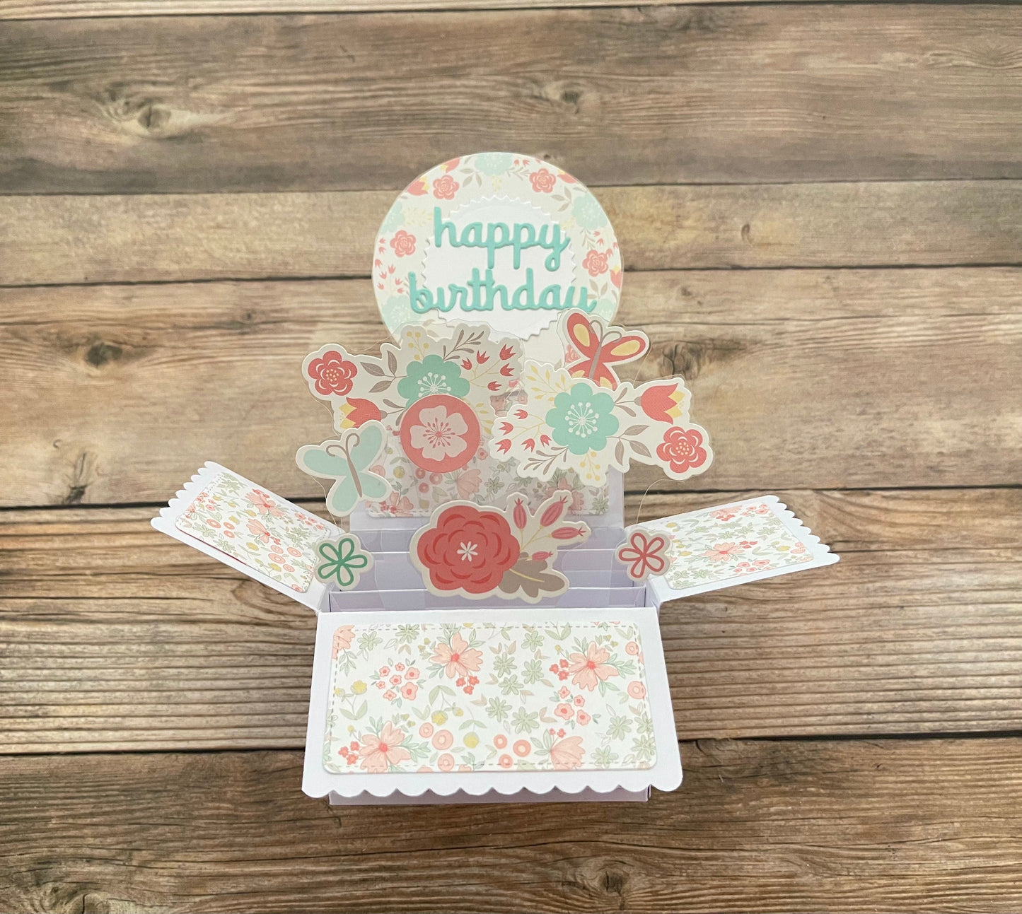 Floral birthday card with 'happy birthday' text on a wooden surface