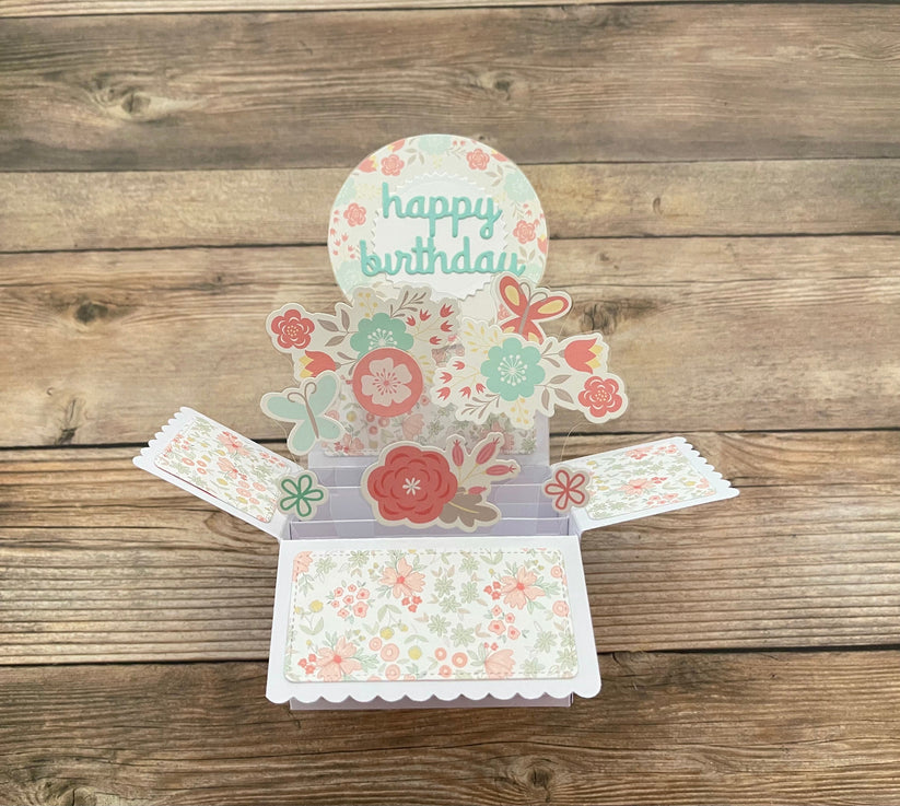 Floral birthday card with 'happy birthday' text on a wooden surface