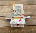 Open pop-up card with kitchen-themed illustrations on a wooden surface