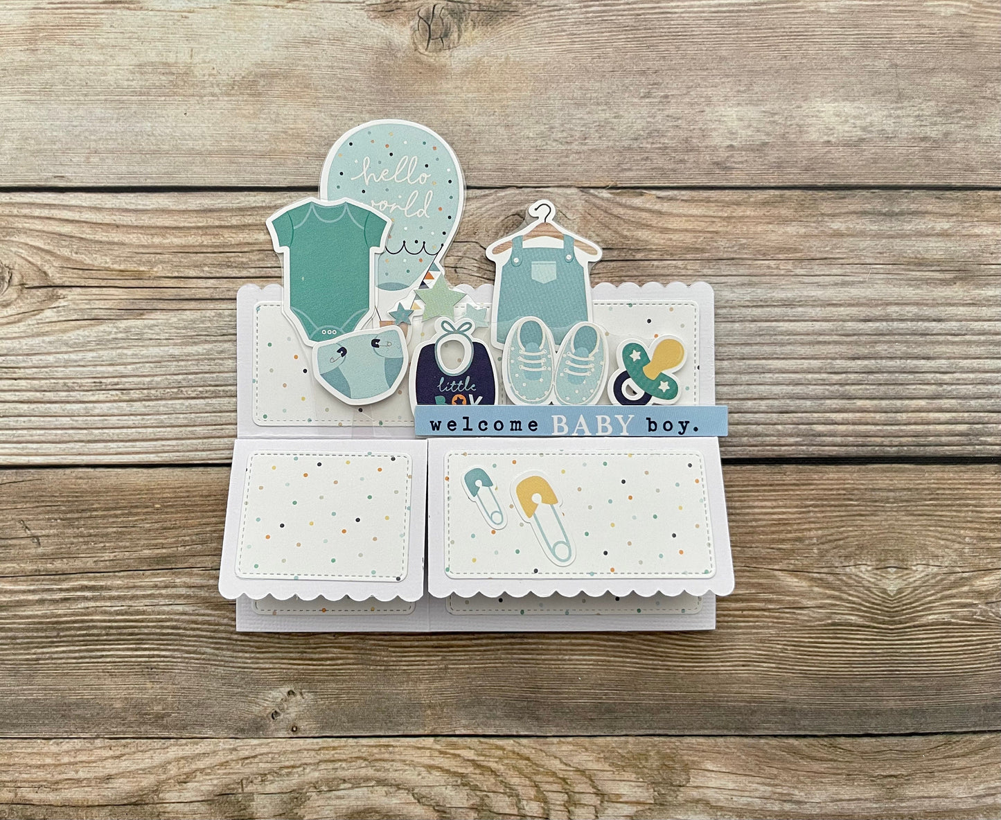 Baby-themed card with illustrations of baby clothes and shoes on a wooden surface
