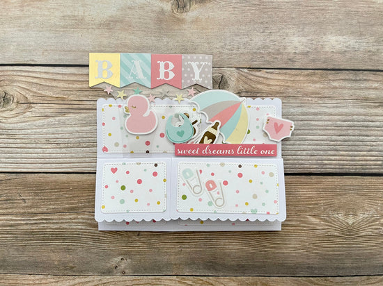 Baby-themed card with colorful elements on a wooden surface