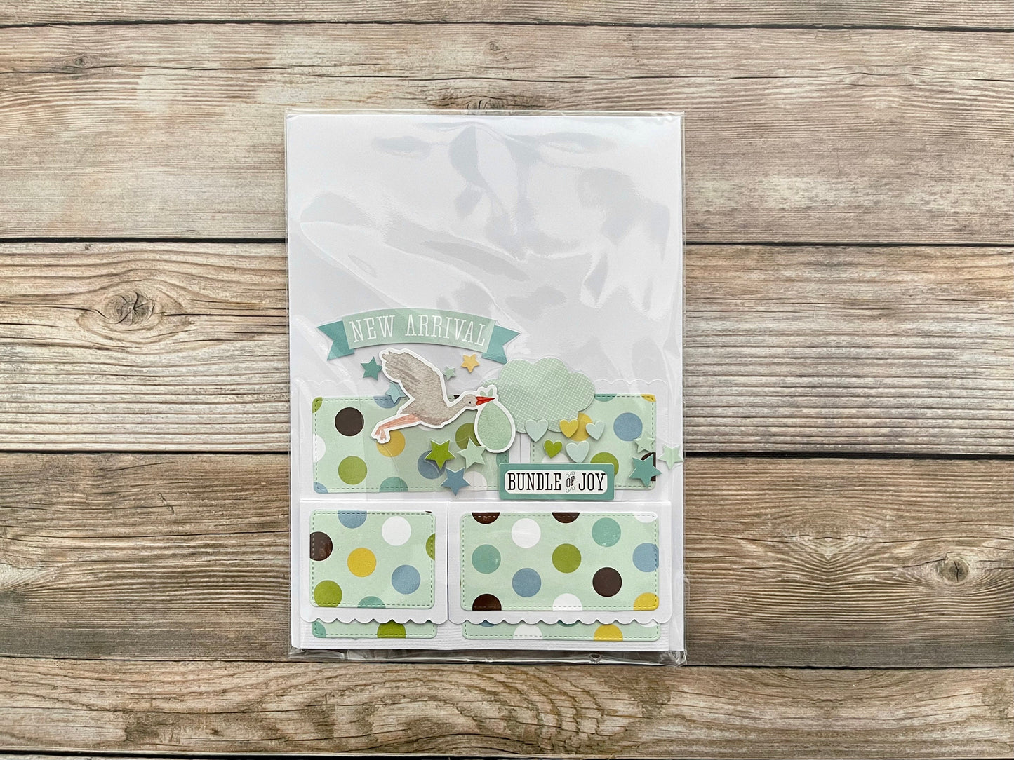 Baby shower card with polka dots and text on a wooden surface