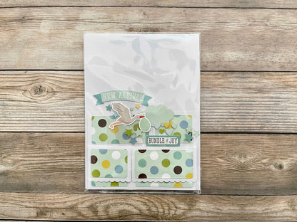 Baby shower card with polka dots and text on a wooden surface