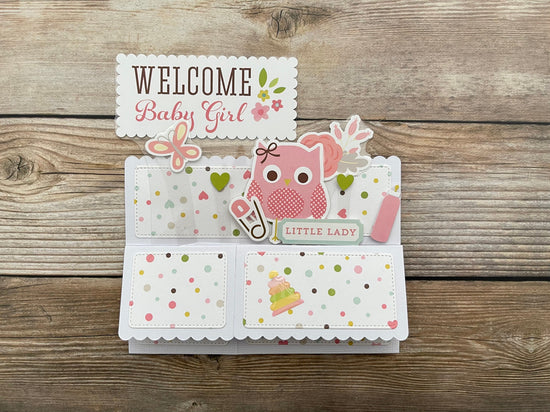 Baby girl-themed card with owl design on a wooden surface