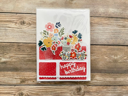 Decorative birthday card with floral designs and 'happy birthday' text on a wooden surface