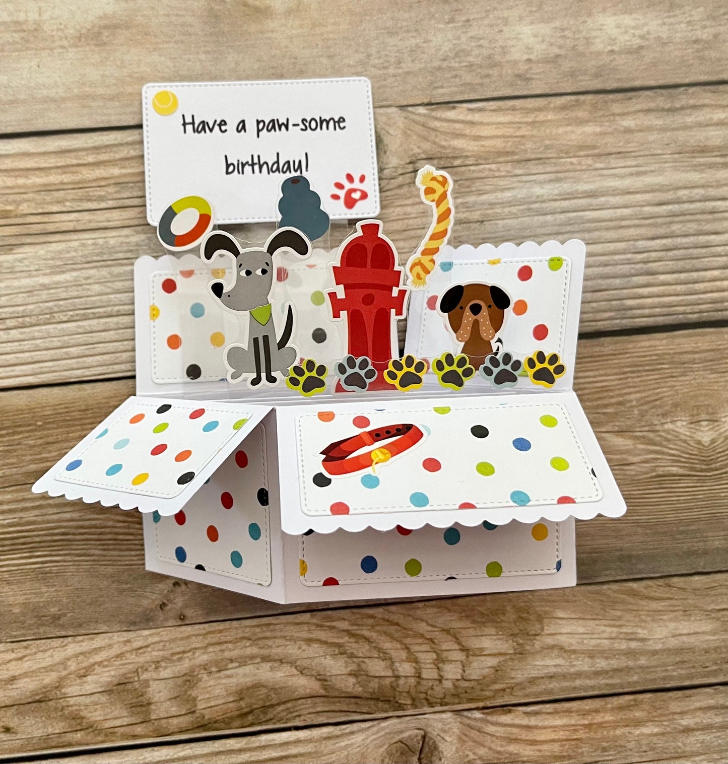 Pop-up birthday card with dog-themed illustrations on a wooden surface