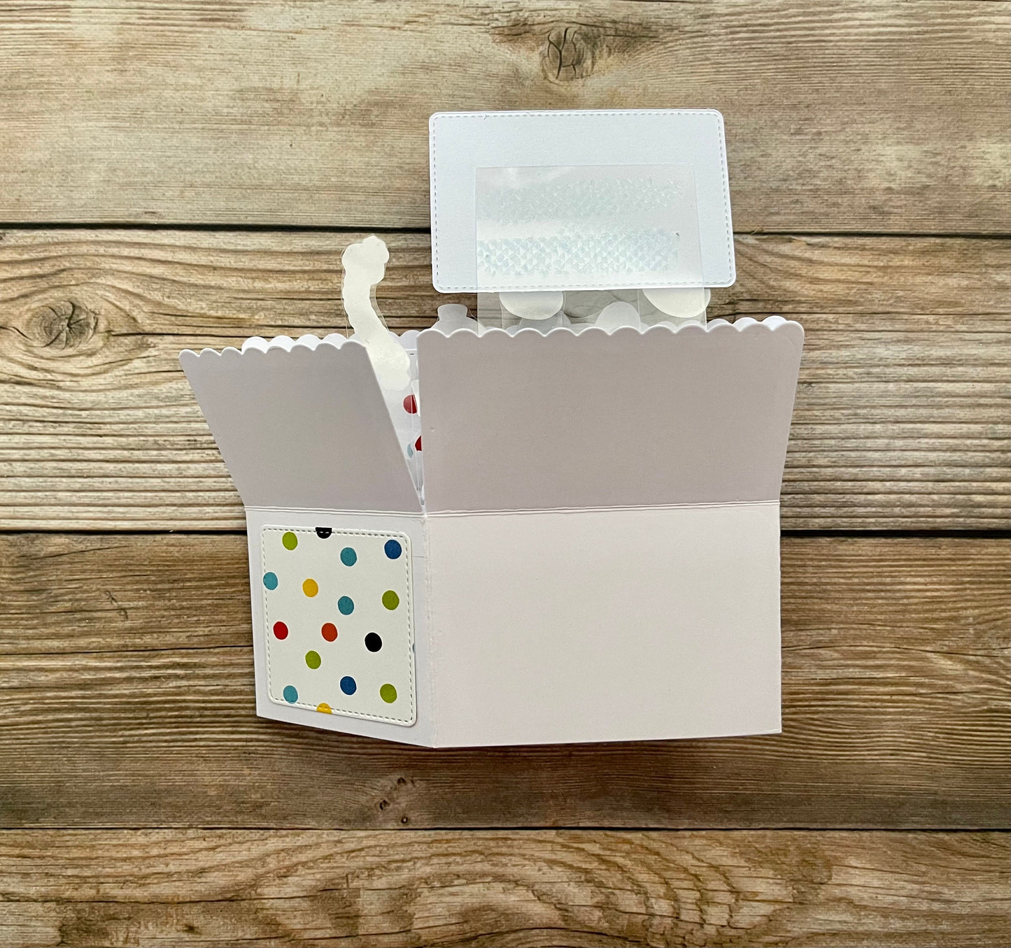 Card with a scalloped edge and colorful polka dot design on a wooden surface