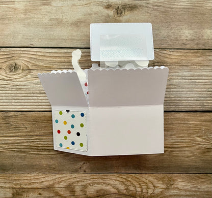 Card with a scalloped edge and colorful polka dot design on a wooden surface