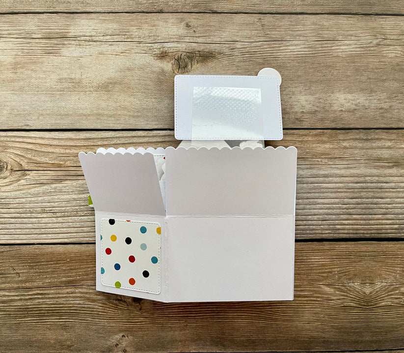 White card with colorful polka dot design on a wooden surface