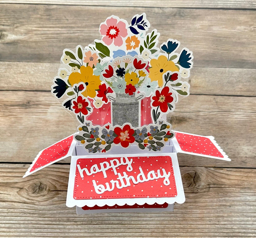 Pop-up birthday card with floral design and 'happy birthday' text on a wooden surface