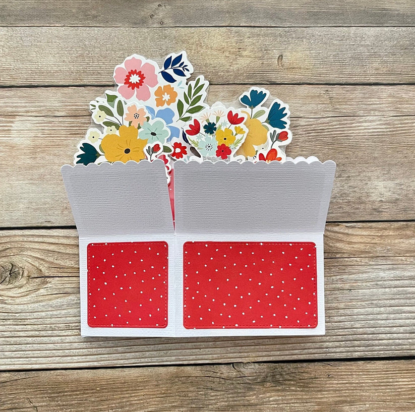 Decorative card with floral design and red polka dot pattern on a wooden surface