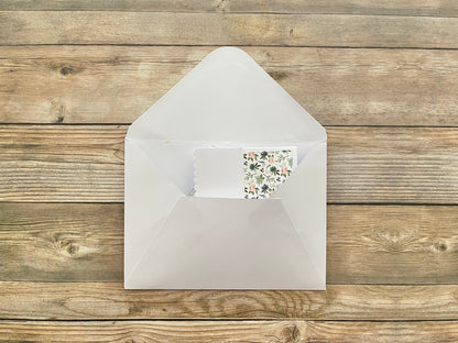 White envelope with a floral card on a wooden surface