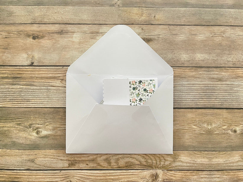 White envelope with a floral card on a wooden surface