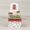 Christmas-themed box style pop-up card with decorative houses and text on a wooden surface.