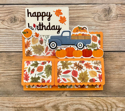 Autumn-themed birthday card with a blue truck and pumpkins on a wooden background