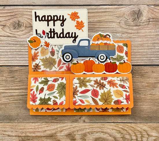 Autumn-themed birthday card with a blue truck and pumpkins on a wooden background