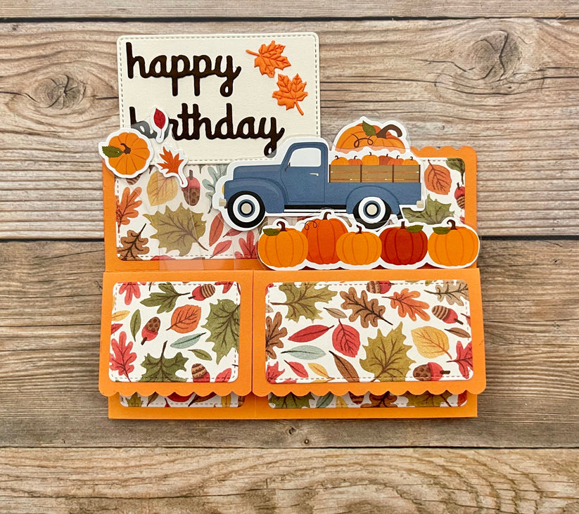 Autumn-themed birthday card with a blue truck and pumpkins on a wooden background
