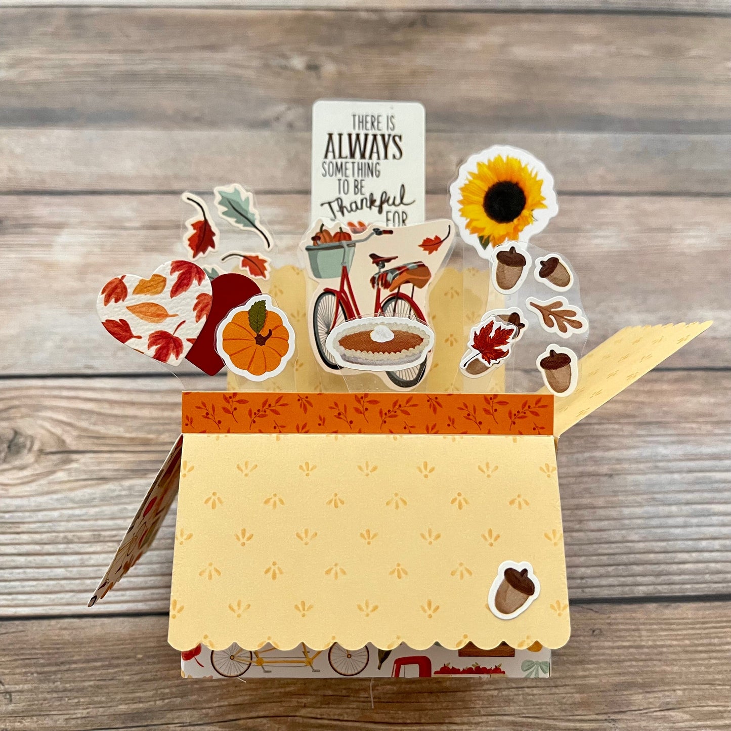 Decorative pop-up card with fall-themed cutouts on a wooden surface