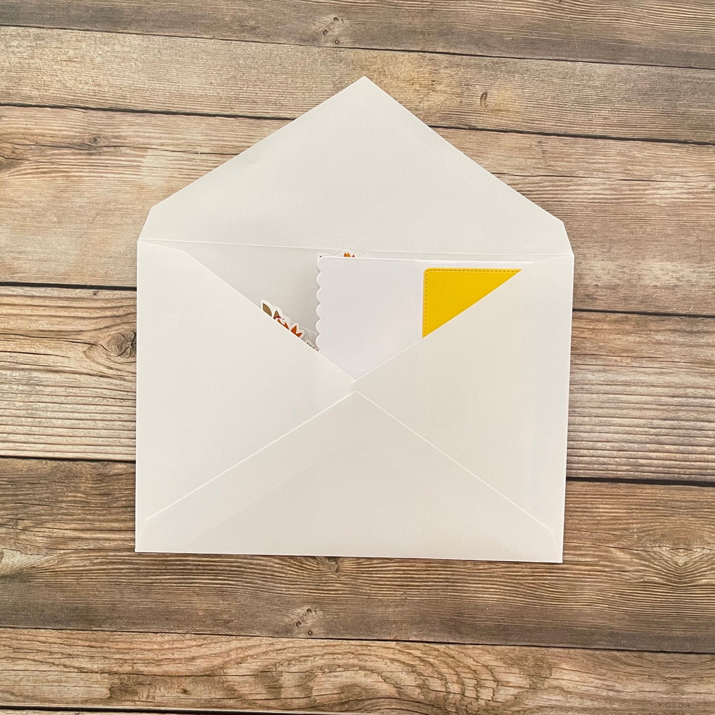 Open white envelope with a yellow corner on a wooden surface