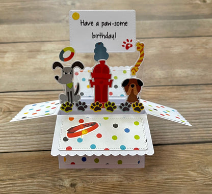 Pop-up birthday card with dog-themed illustrations on a wooden surface