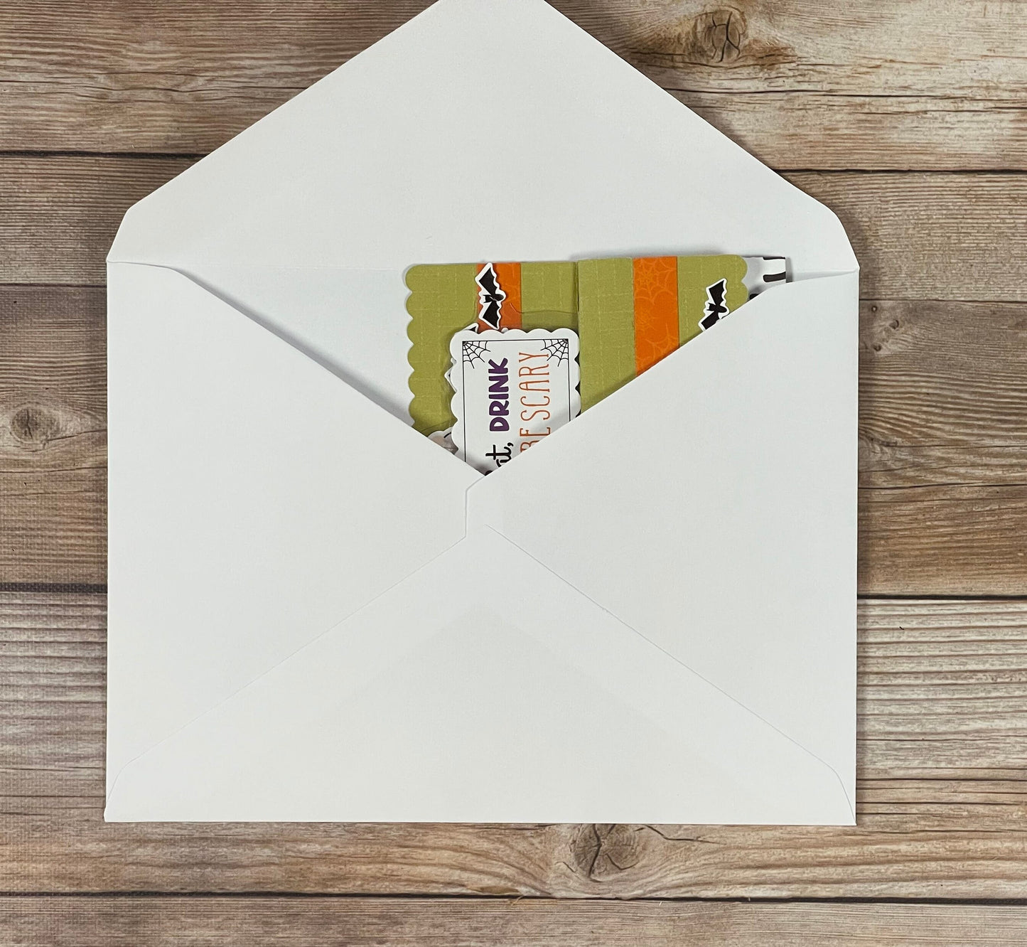 Open white envelope with Halloween-themed cards on a wooden surface