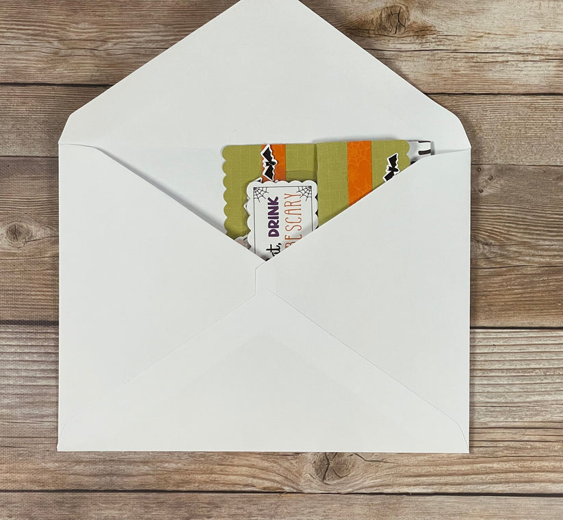 Open white envelope with Halloween-themed cards on a wooden surface