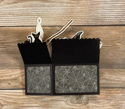 Black Halloween-themed box with spider web pattern on a wooden surface