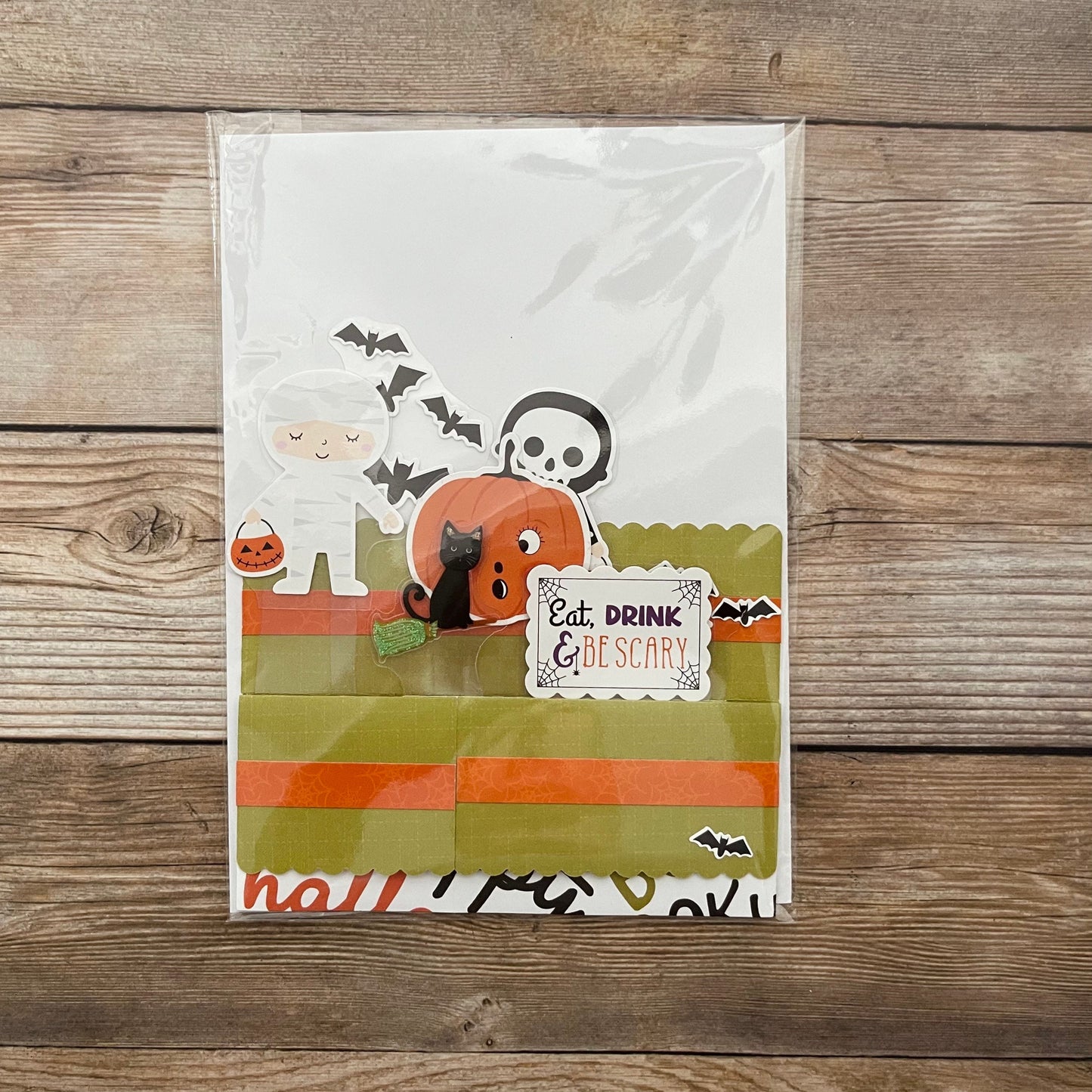 Halloween-themed pop-up card with ghost, pumpkin, and cat design on a wooden surface