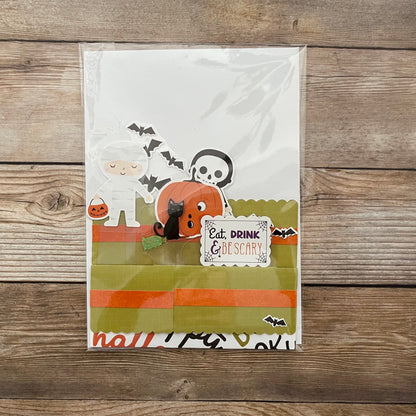Halloween-themed pop-up card with ghost, pumpkin, and cat design on a wooden surface