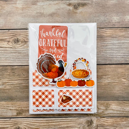 Thanksgiving-themed card with illustrations of a turkey, pie, and pumpkins on a wooden background.