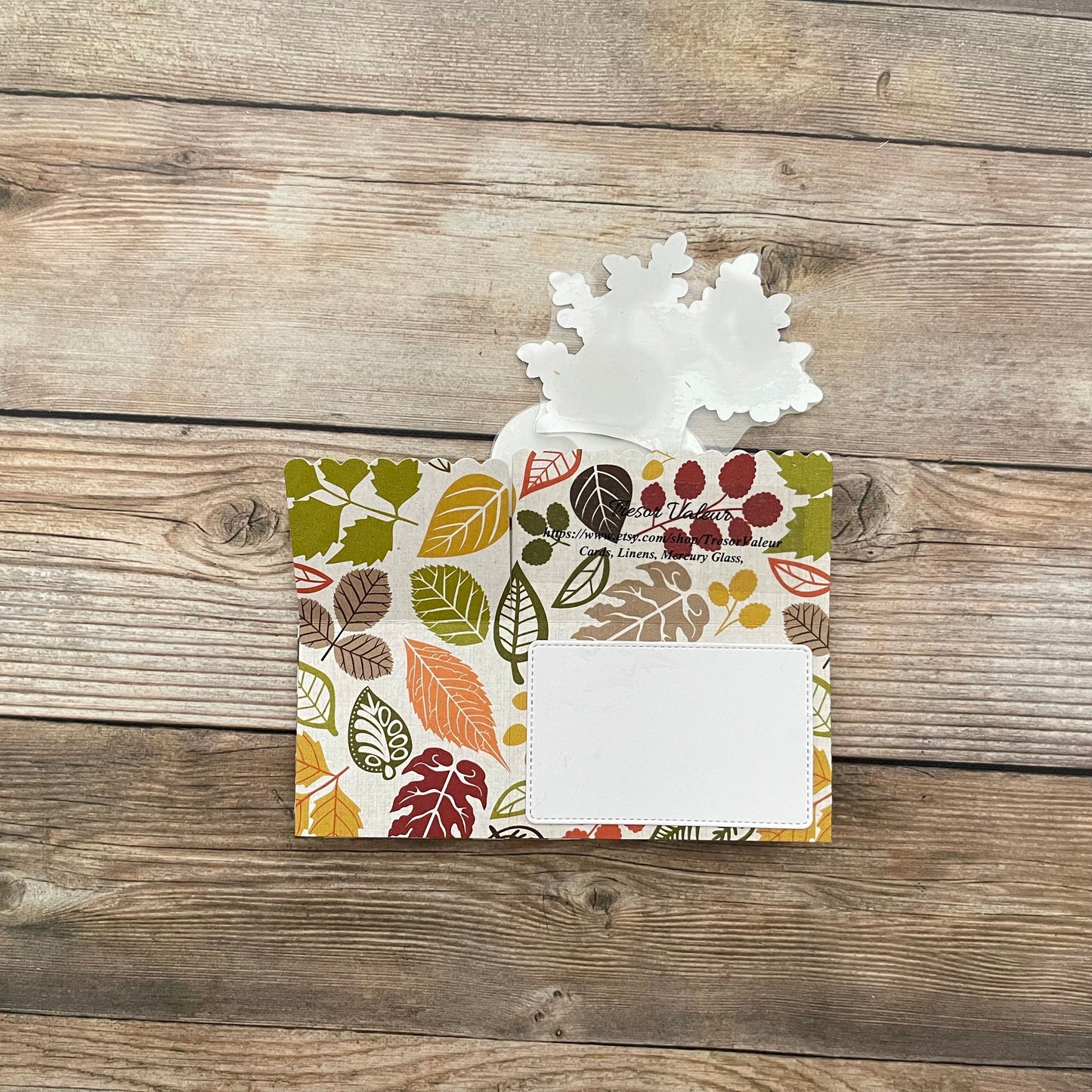 Decorative envelope with autumn leaf pattern on a wooden surface