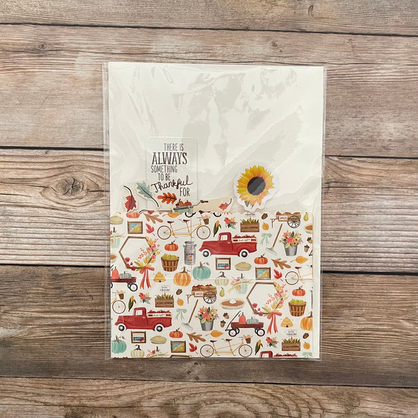 Decorative greeting card with autumn-themed illustrations and text on a wooden surface