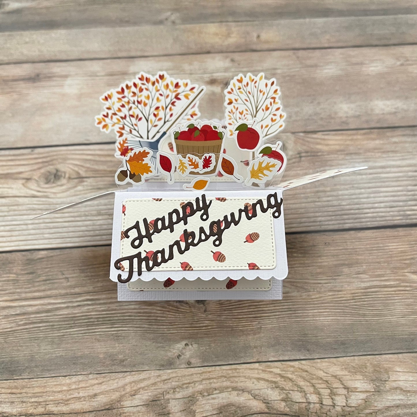 Thanksgiving-themed card with fall decorations on a wooden surface