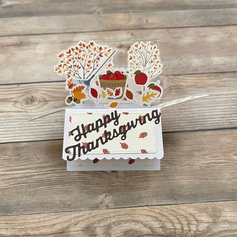 Thanksgiving-themed card with fall decorations on a wooden surface