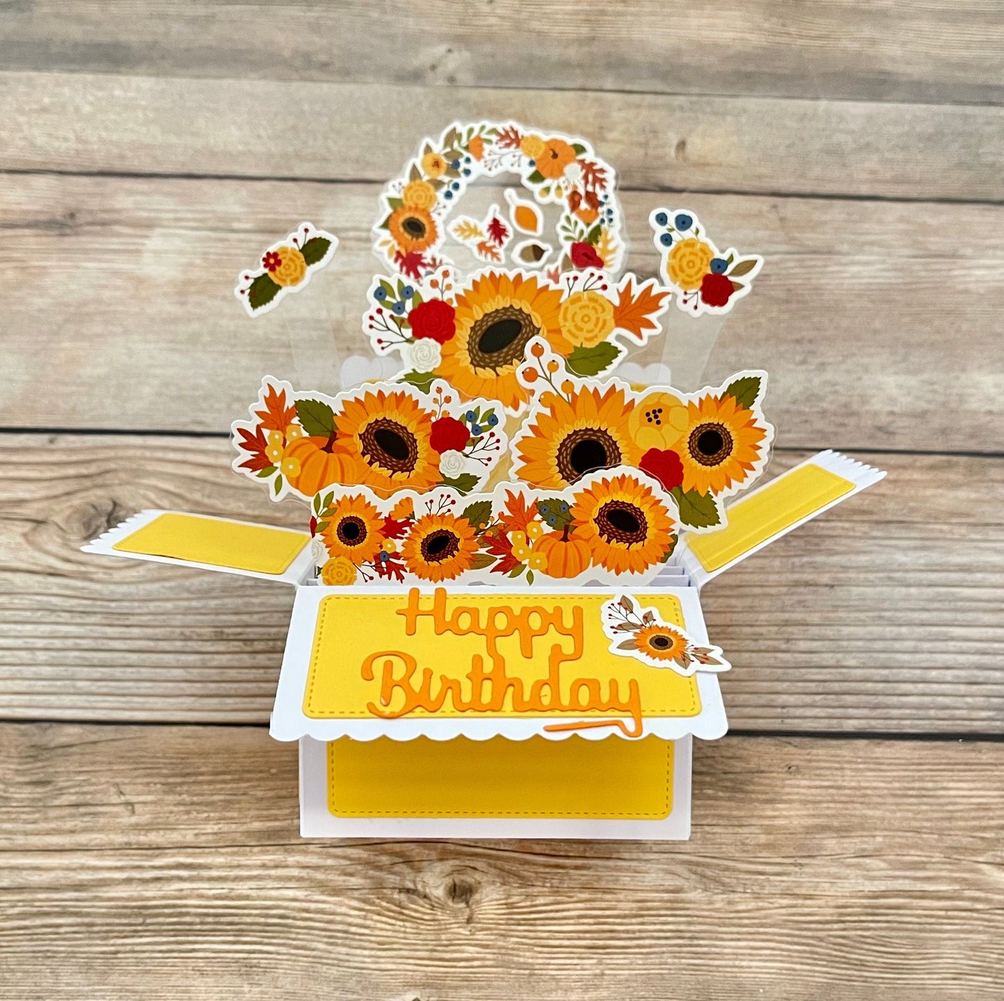 Pop-up birthday card with sunflowers and 'Happy Birthday' text on a wooden surface