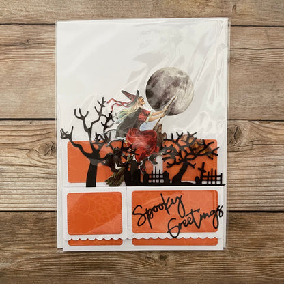 Halloween-themed card with witch and moon design on a wooden surface