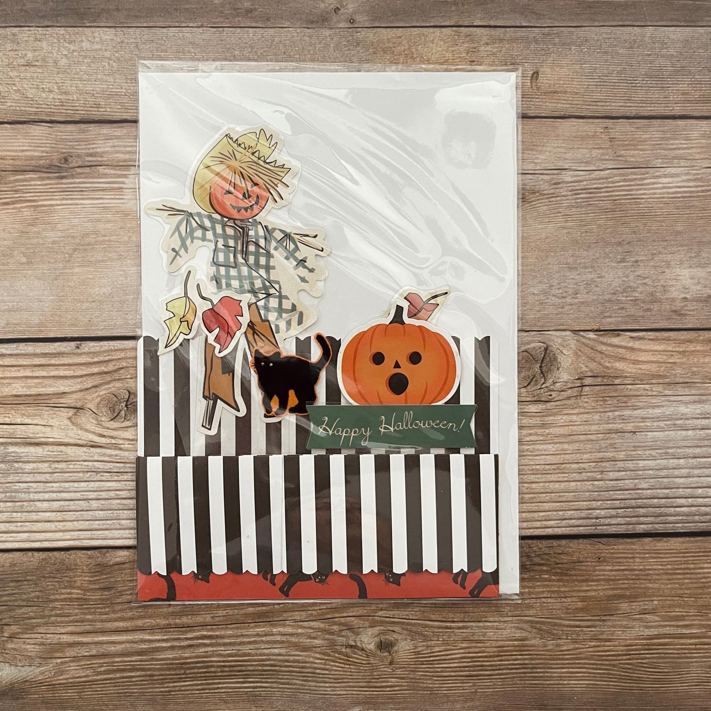 Halloween-themed greeting card with scarecrow, dog, and pumpkin on a wooden background