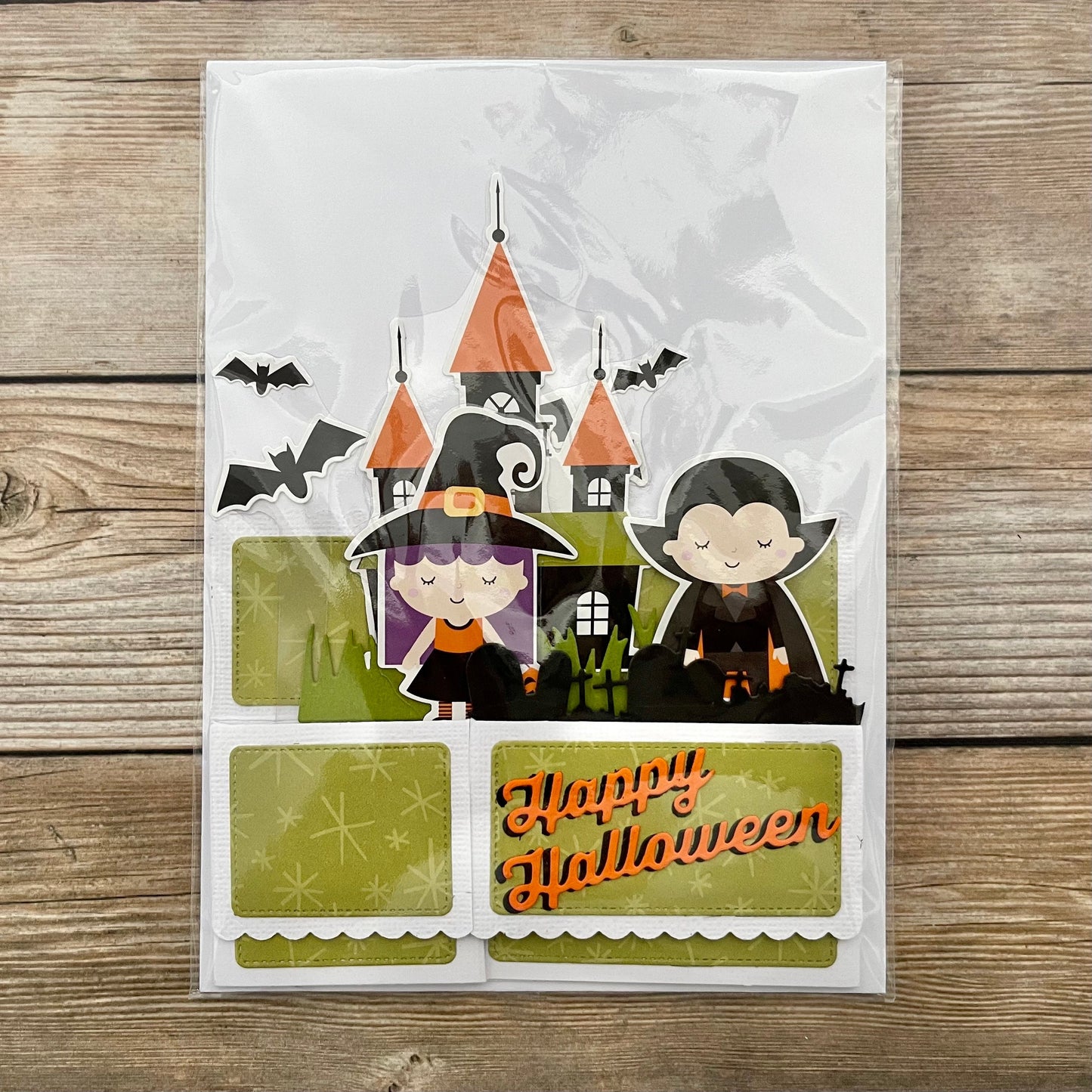 Halloween-themed card with cartoon characters and castle on a wooden surface