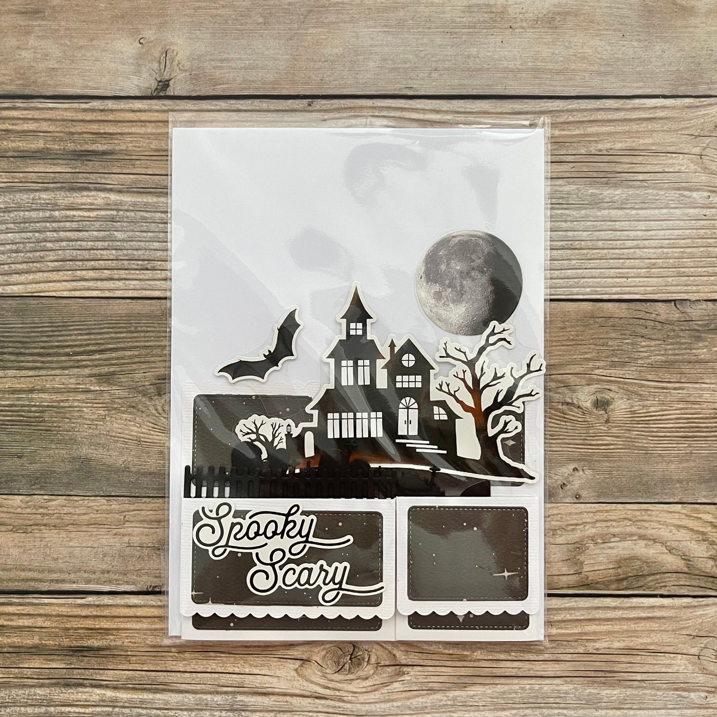 Halloween-themed decorative paper cutout with a haunted house design on a wooden surface.
