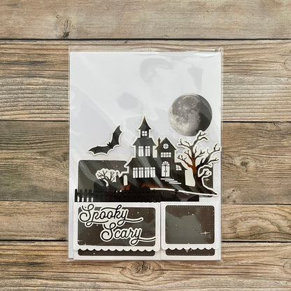 Halloween-themed decorative paper cutout with a haunted house design on a wooden surface.