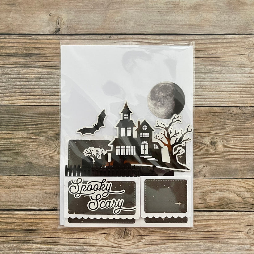 Halloween-themed decorative paper cutout with a haunted house design on a wooden surface.